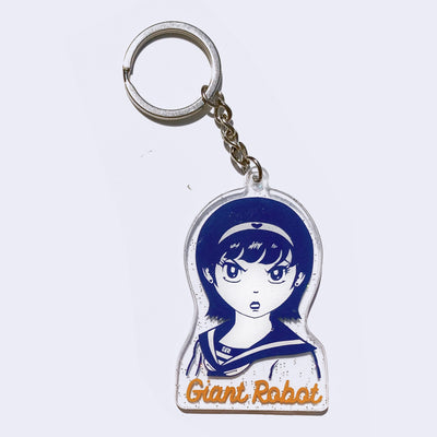 Die cut clear acrylic keychain of an illustration of a dark blue manga girl with an angry expression, "GR" is written on the collar of her sailor-style shirt. "Giant Robot" is written in orange cursive font below the design.