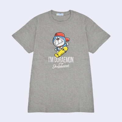 Gray t-shirt with an illustrated graphic of Doraemon, a blue earless cat character, wearing a backwards red hat and riding a yellow skateboard. Text reads "I'm Doraemon plays skateboard"