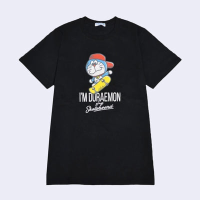 Black t-shirt with an illustrated graphic of Doraemon, a blue earless cat character, wearing a backwards red hat and riding a yellow skateboard. Text reads "I'm Doraemon plays skateboard"