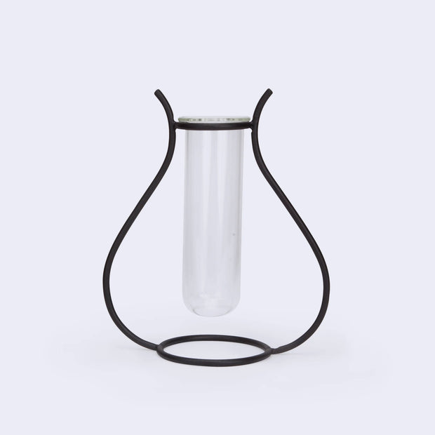 A silhouetted vase made of iron holding a glass tube inside.