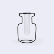 A silhouetted vase made of iron holding a glass tube inside.