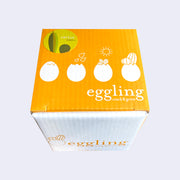White cardboard box for "Eggling Crack & Grow". Seen overhead to show the stages of the egg while growing a plant inside.
