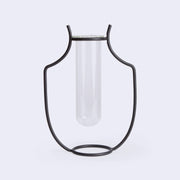 A silhouetted vase made of iron holding a glass tube inside.