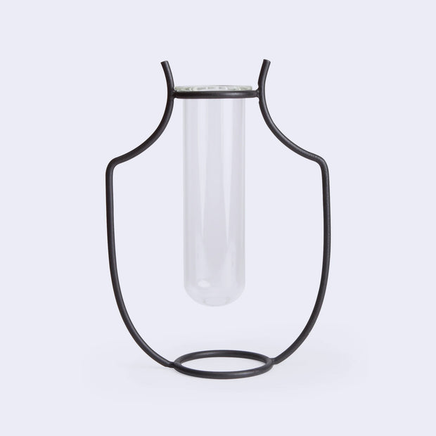 A silhouetted vase made of iron holding a glass tube inside.