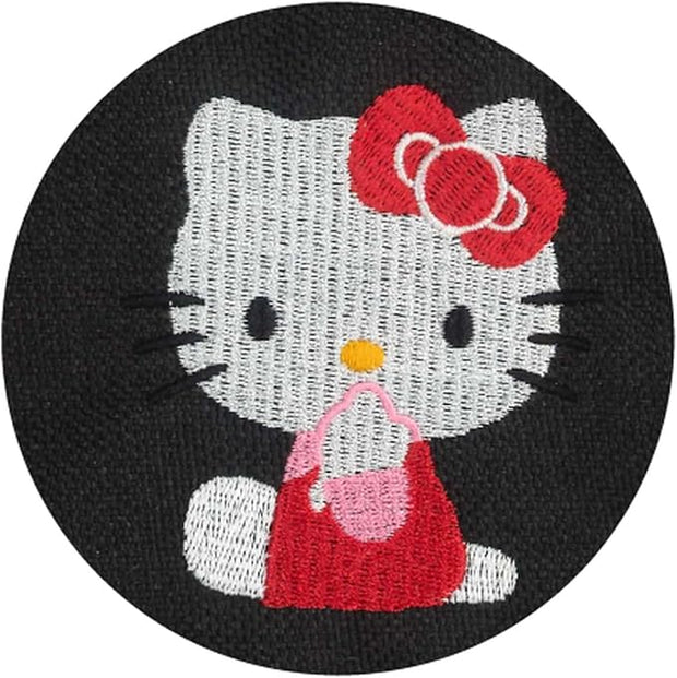 Close up of embroidery of Hello Kitty, sitting on the ground and looking to the side with her hand over her mouth.