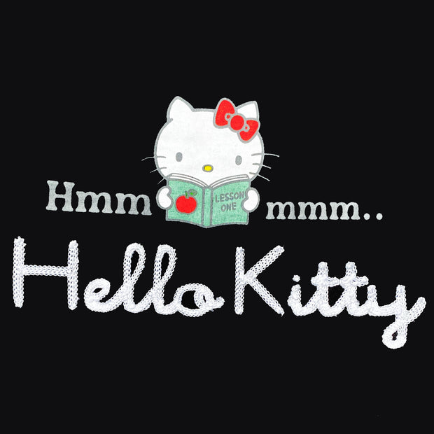 Black long sleeve shirt with a graphic in the center of Hello Kitty reading a book. Around her says "Hmmmmm.." with half the text on one side and the other half on the other. Below is a white yarn embroidered element spelling out "Hello Kitty".