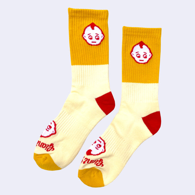 Pair of socks, mostly light yellow with a block of mustard yellow and red accents. A small kewpie head is on the ankle with another on the foot with "Giant Robot" written underneath.