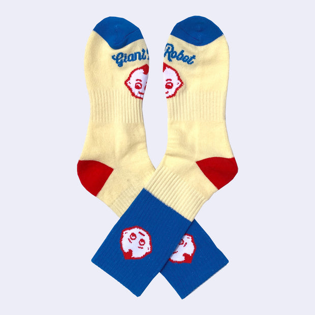 Pair of socks, mostly light yellow with a block of blue and red accents. A small kewpie head is on the ankle with another on the foot with "Giant Robot" written underneath.