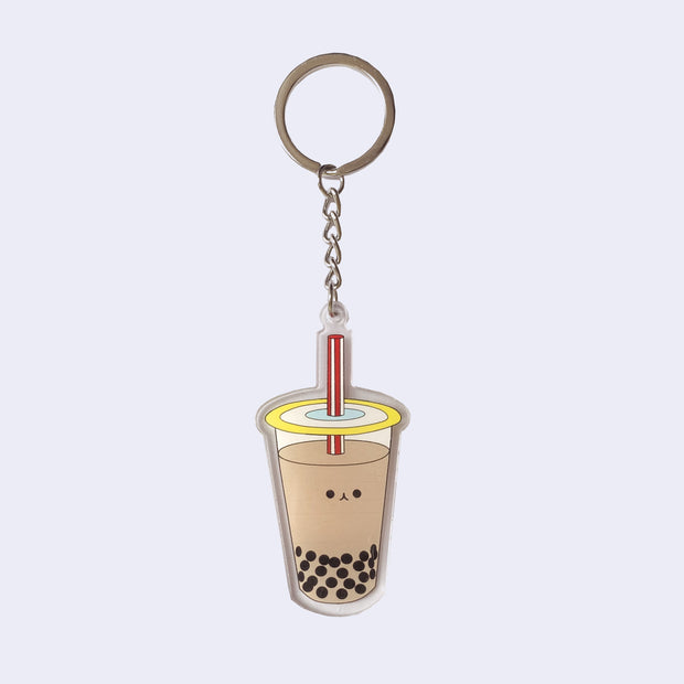 Die cut acrylic keychain of an illustrated milk tea boba cup with a small smiling cartoon style face in the center of the cup.