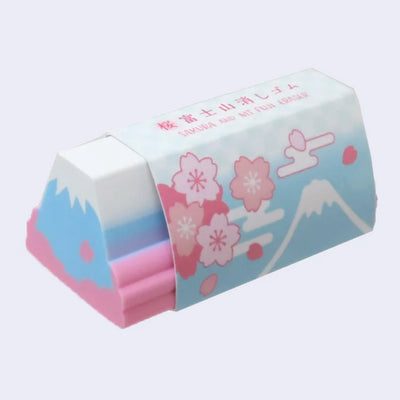 Eraser shaped like a long cylinder version of Mt Fuji, blue with a white snow capped top. At its sides are pink flowers.